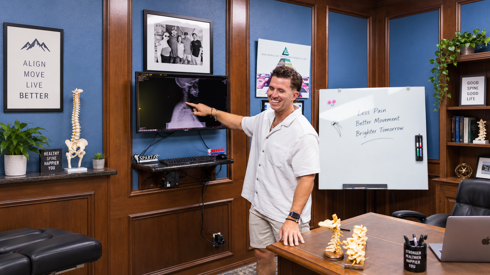 Chiropractor reviewing spinal X-ray images on a wall-mounted display screen