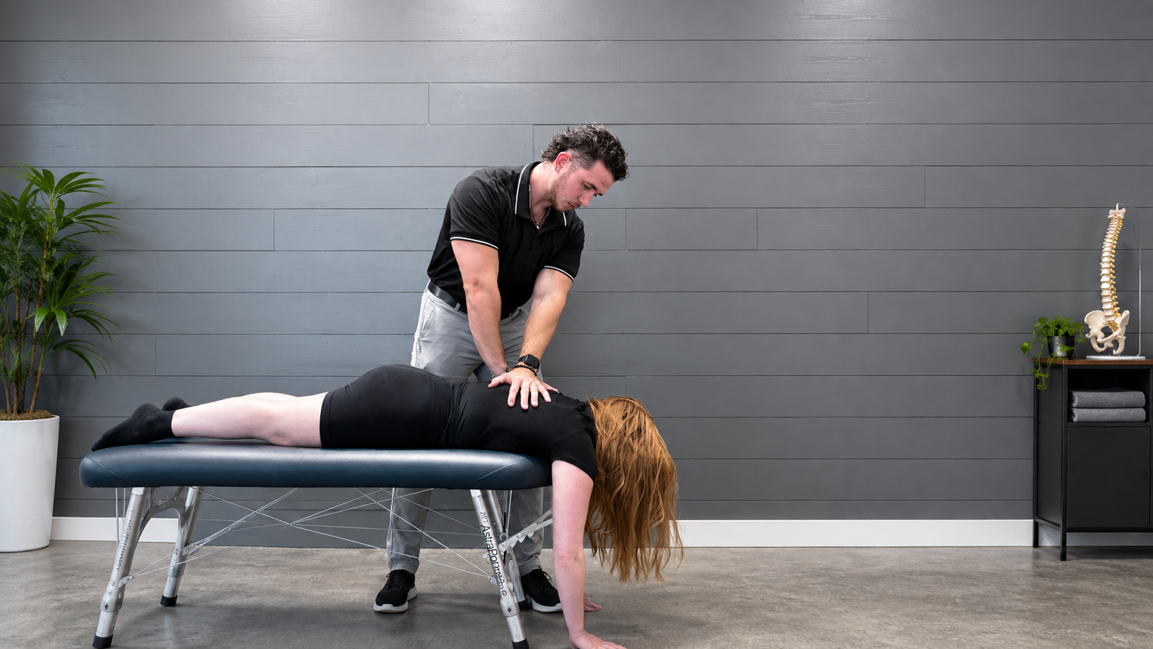 Chiropractor performing a spinal adjustment on a patient lying face-down on a treatment table