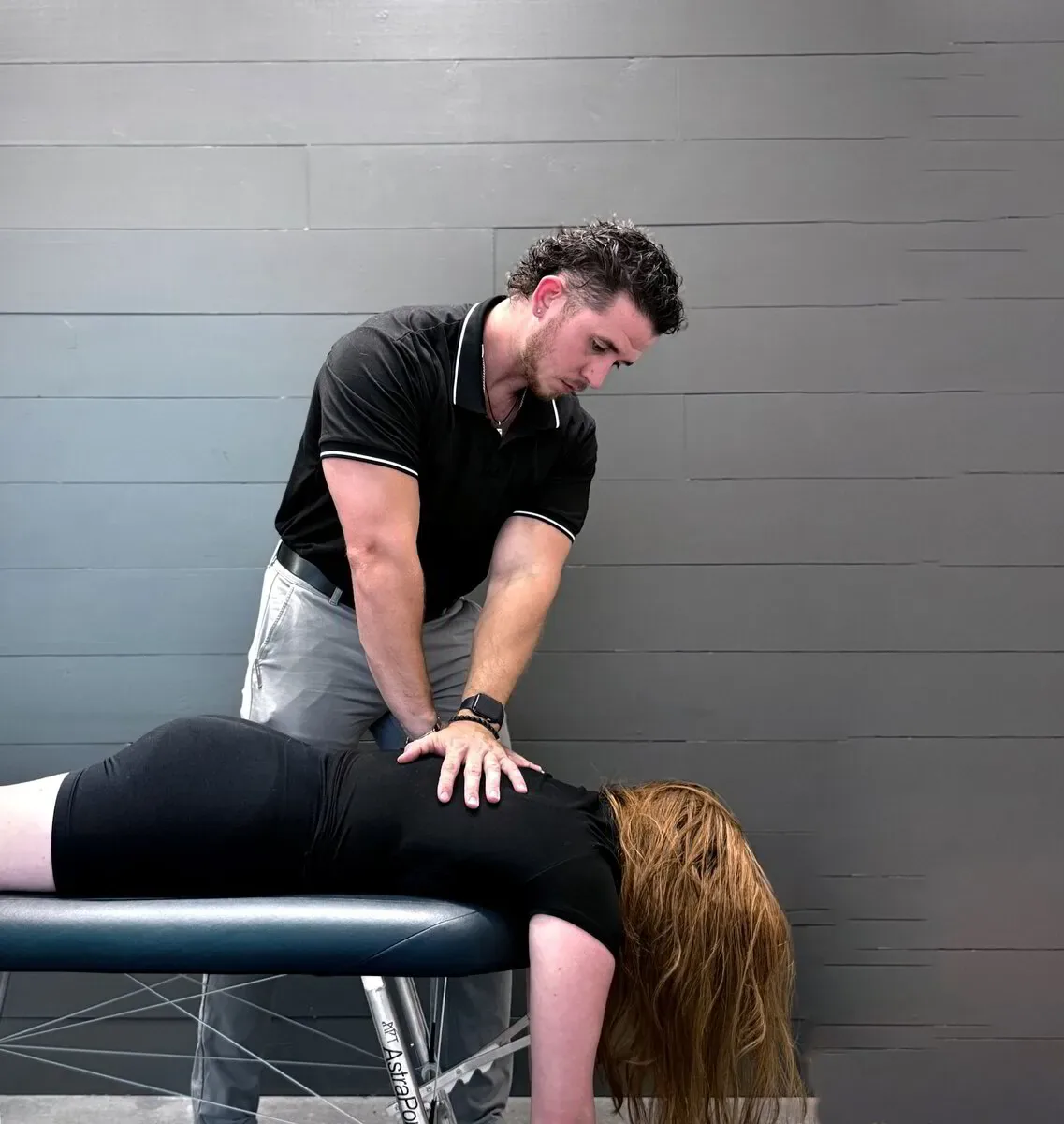 Dr. Levi Hansen performs a spinal adjustment on a patient lying face down on a treatment table.