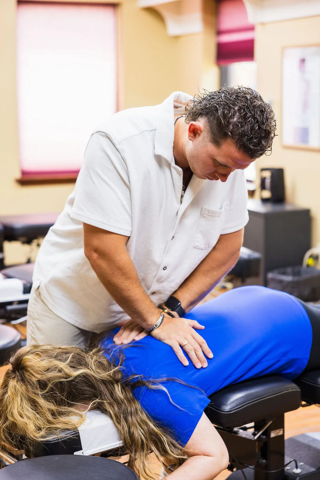 Dr. Levi Hansen performs a hands-on spinal adjustment on a patient lying prone on a treatment table.