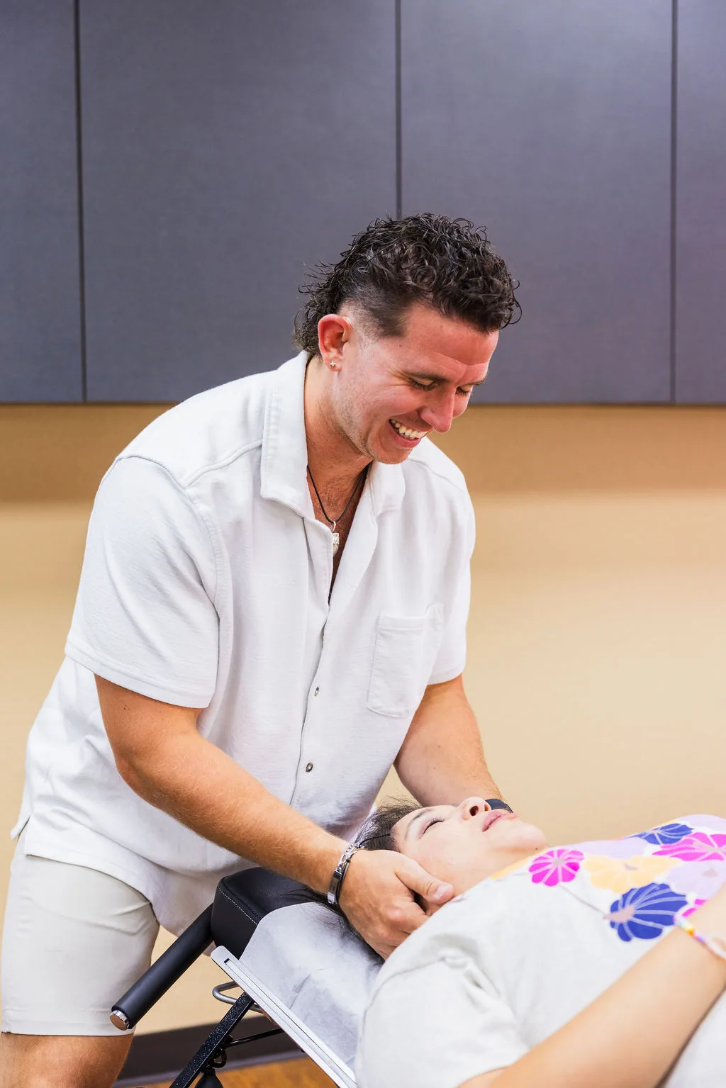 Dr. Levi Hansen smiles while performing a cervical adjustment on a patient lying on a treatment table.