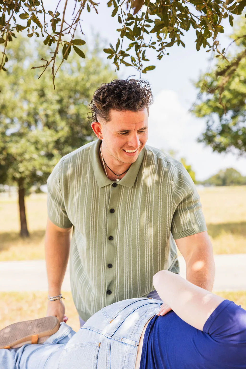 Dr. Levi Hansen smiling while performing an outdoor chiropractic adjustment on a patient.