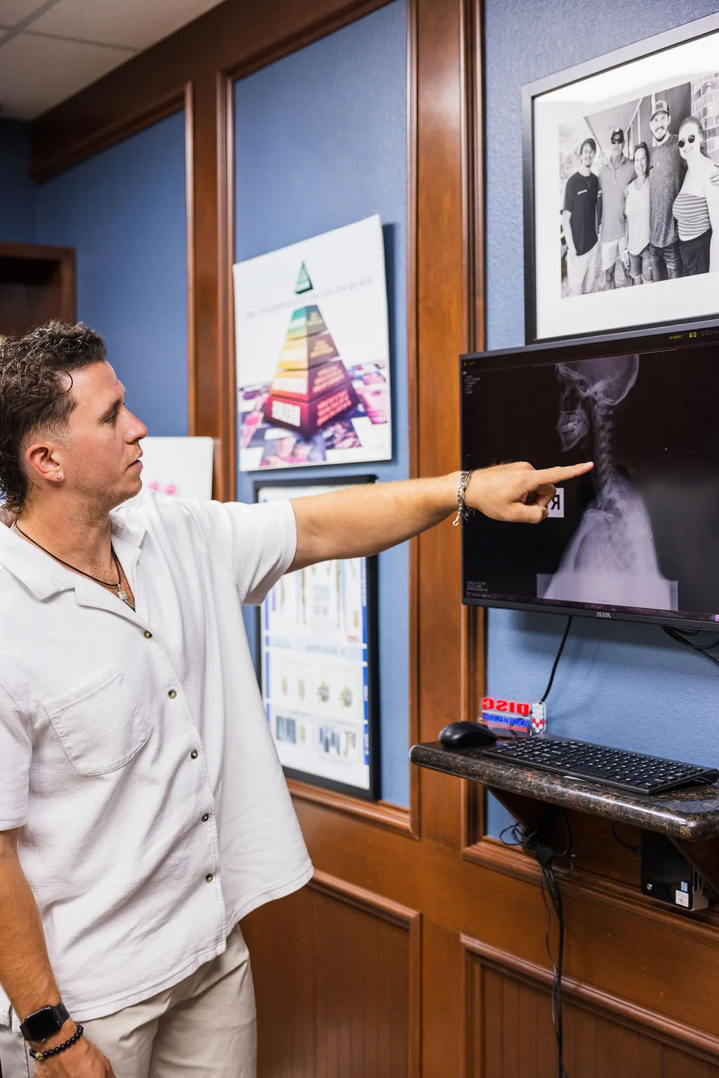 Dr. Levi Hansen points to a cervical spine X-ray displayed on an office computer monitor.