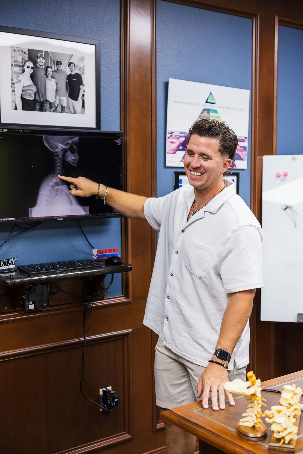 Dr. Levi Hansen smiles as he points to a cervical spine X-ray on an office monitor.