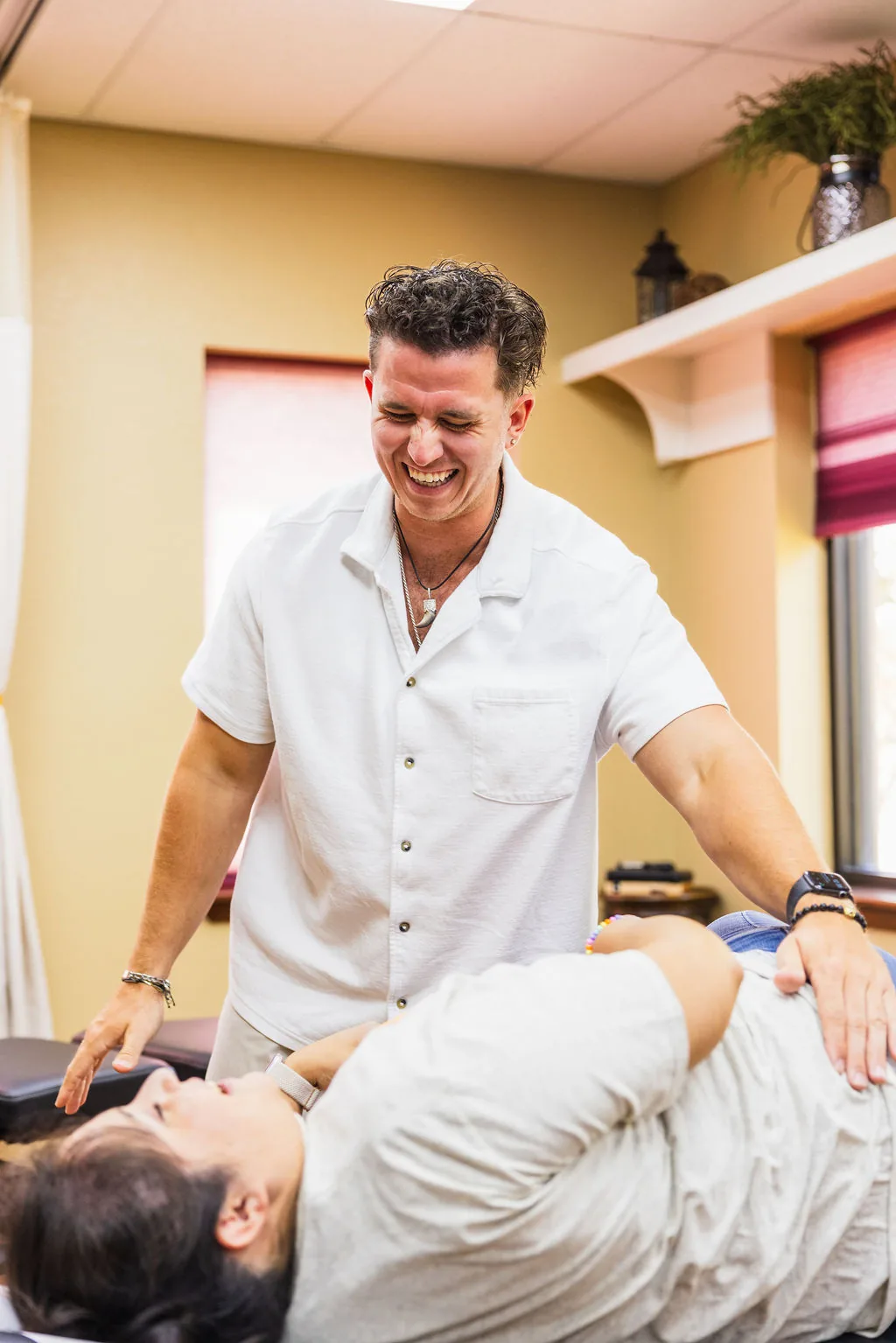 Dr. Levi Hansen smiles while adjusting a patient resting on a treatment table.