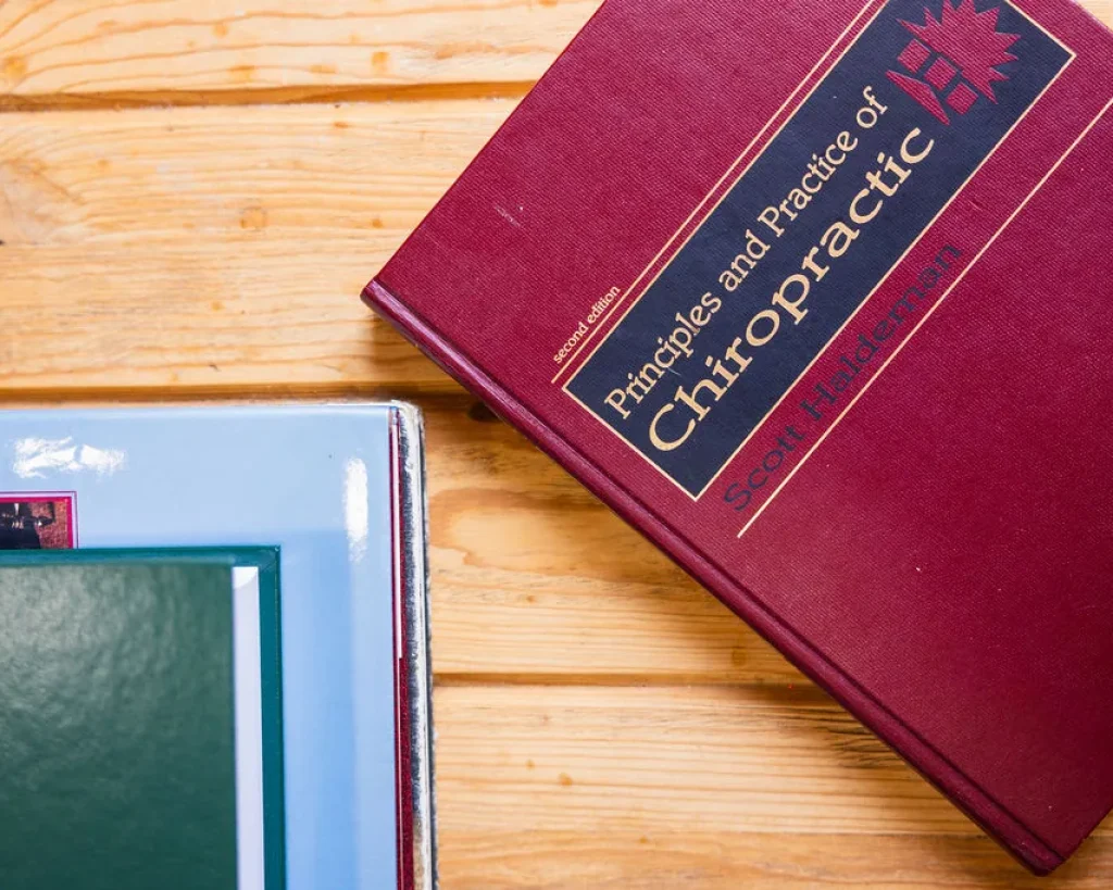 Principles and Practice of Chiropractic textbook resting on a wooden tabletop.