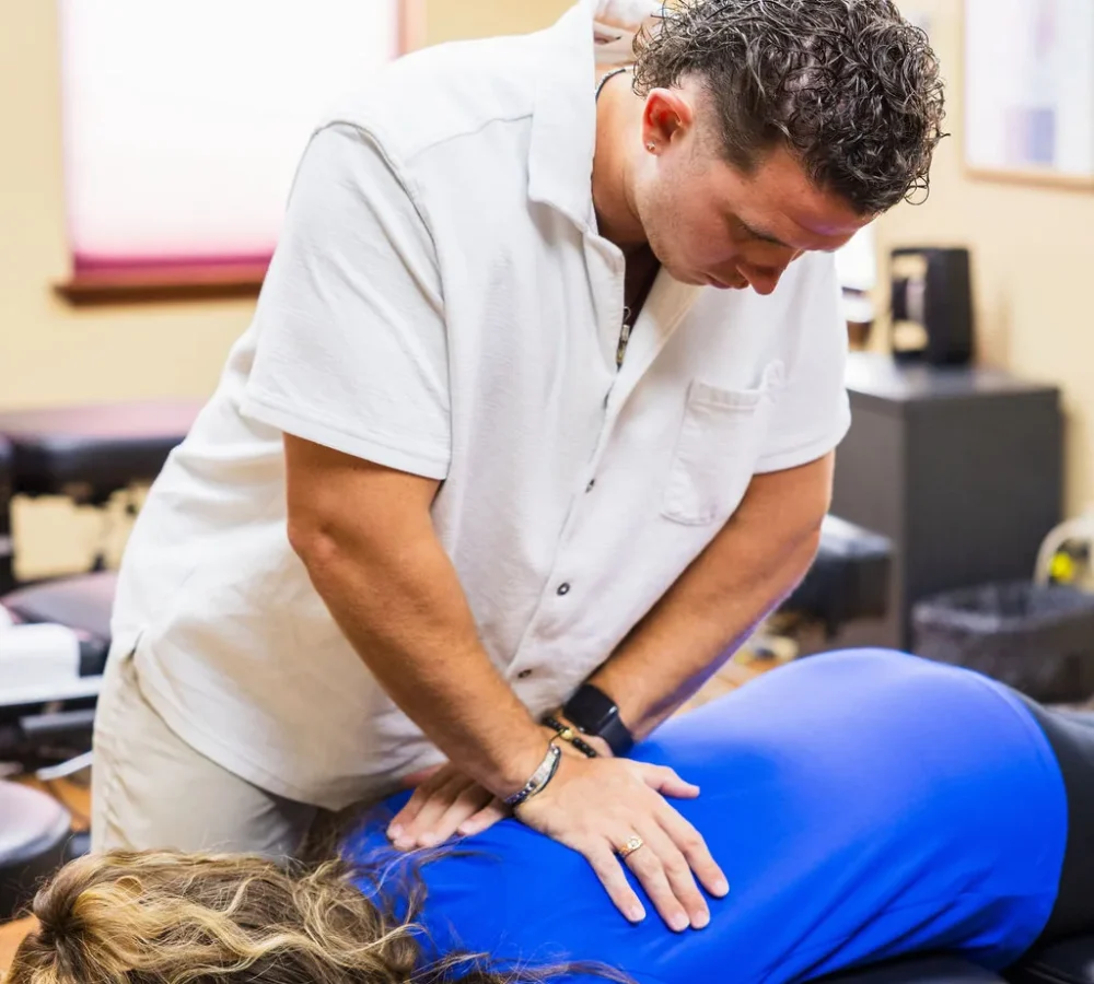 Dr. Levi Hansen performs a hands-on spinal adjustment on a patient lying prone on a treatment table.