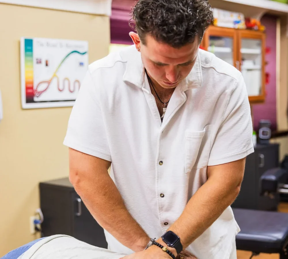 Dr. Levi Hansen performs a thoracic spine adjustment on a patient lying face down on a treatment table.