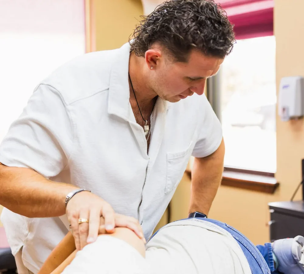 Dr. Levi Hansen performs a side-posture chiropractic adjustment on a patient lying on an exam table.