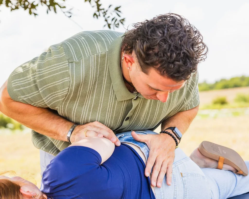 Dr. Levi Hansen performs a chiropractic adjustment on a patient resting on a portable table outdoors.