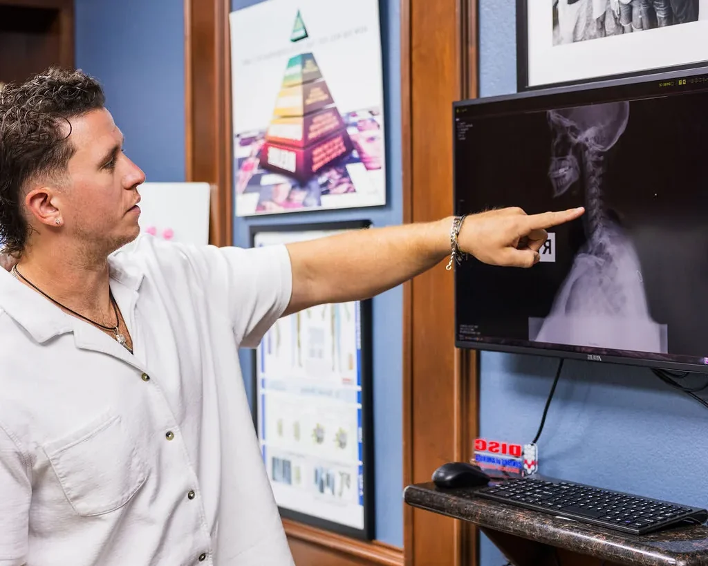 Dr. Levi Hansen points to a cervical spine X-ray displayed on an office computer monitor.