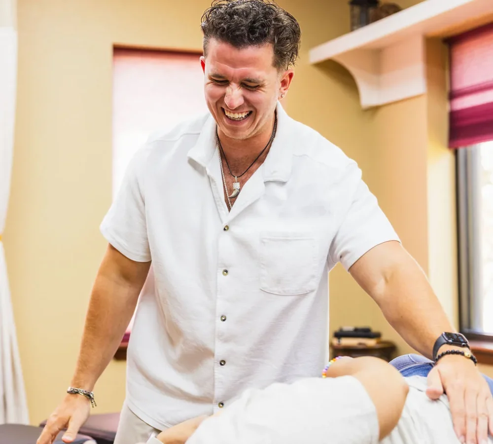 Dr. Levi Hansen smiles while adjusting a patient resting on a treatment table.
